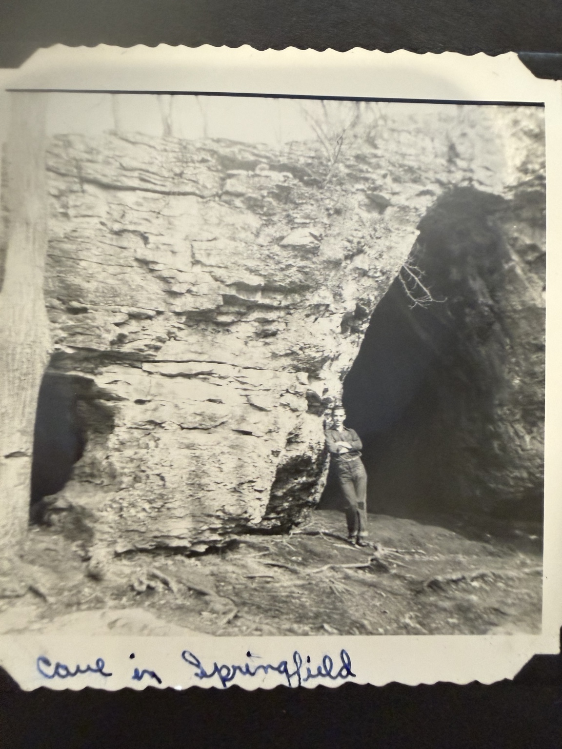 A person beside a dry cave opening at Sequiota, with the handwritten caption “Cave in Springfield.”