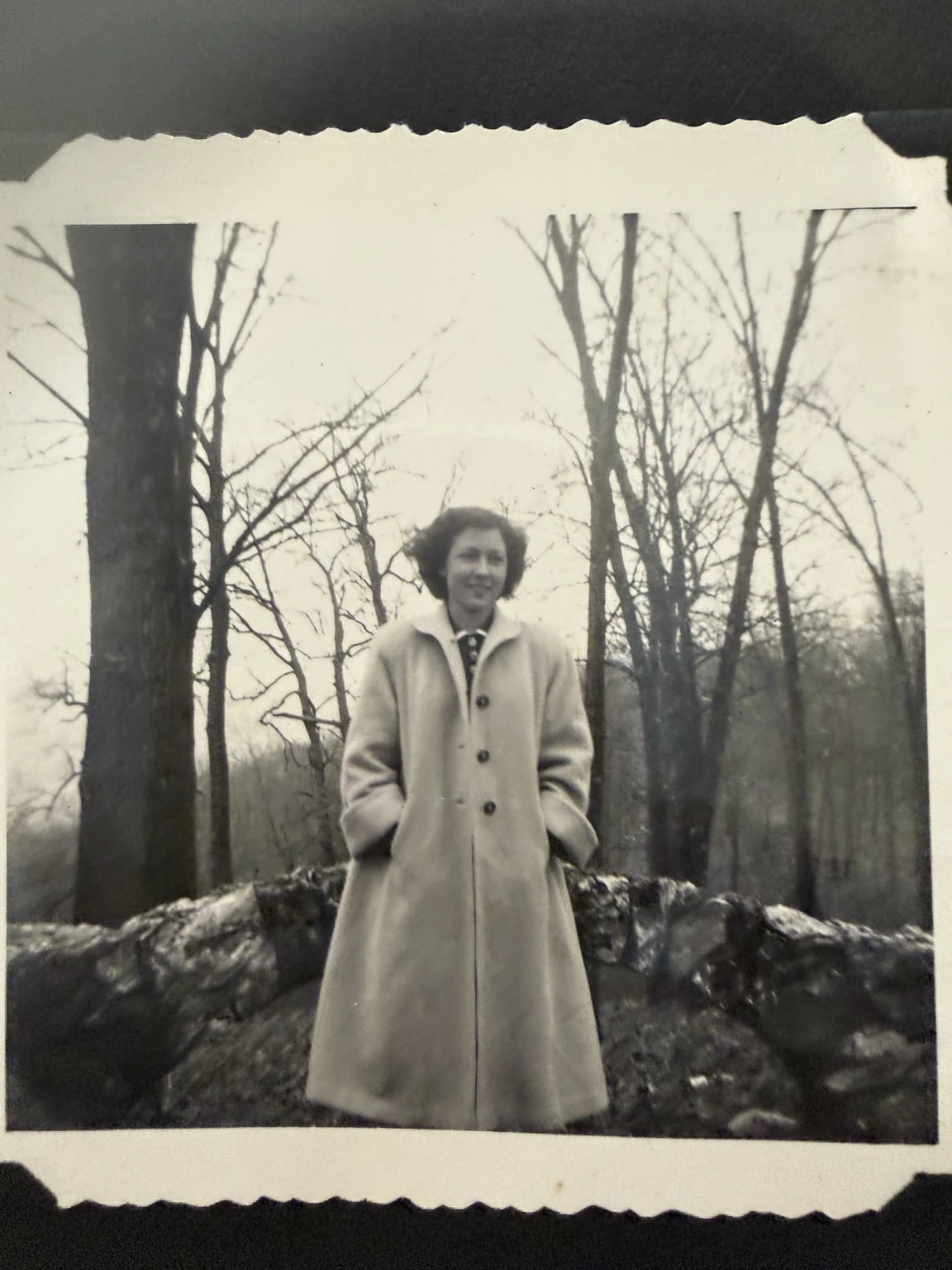 Bridget, identified in the family collection, standing outdoors beside a low stone wall. Exact place and date are unconfirmed.