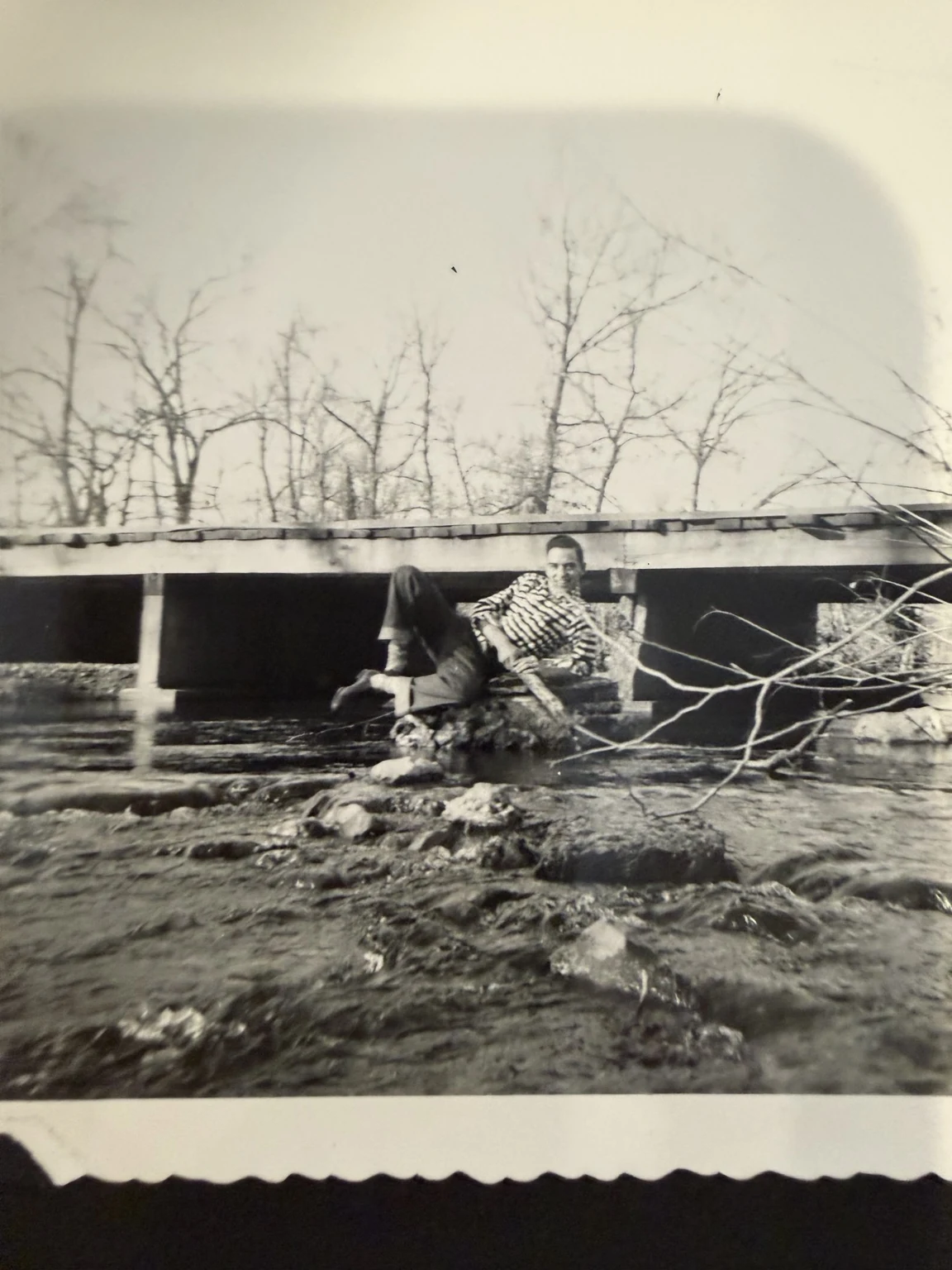 Bob, identified in the family collection, beside a stream near a bridge. Exact waterway and date are unconfirmed.