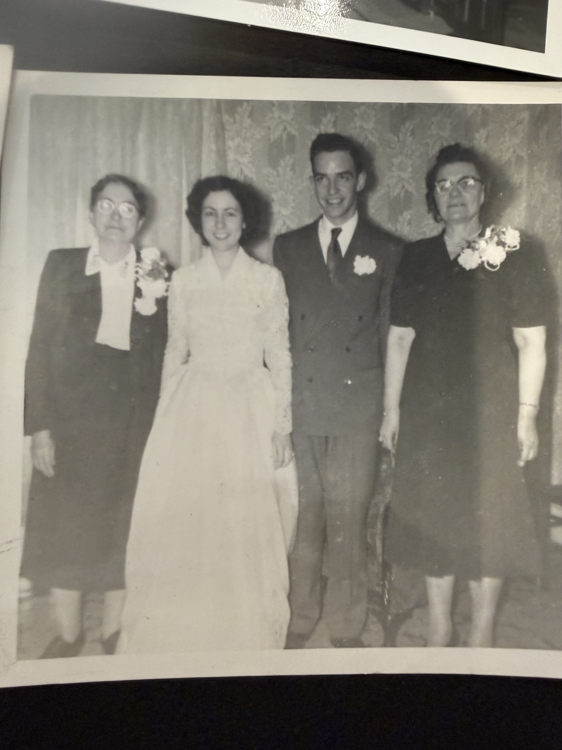 Bride and groom posed with two women against patterned wallpaper.