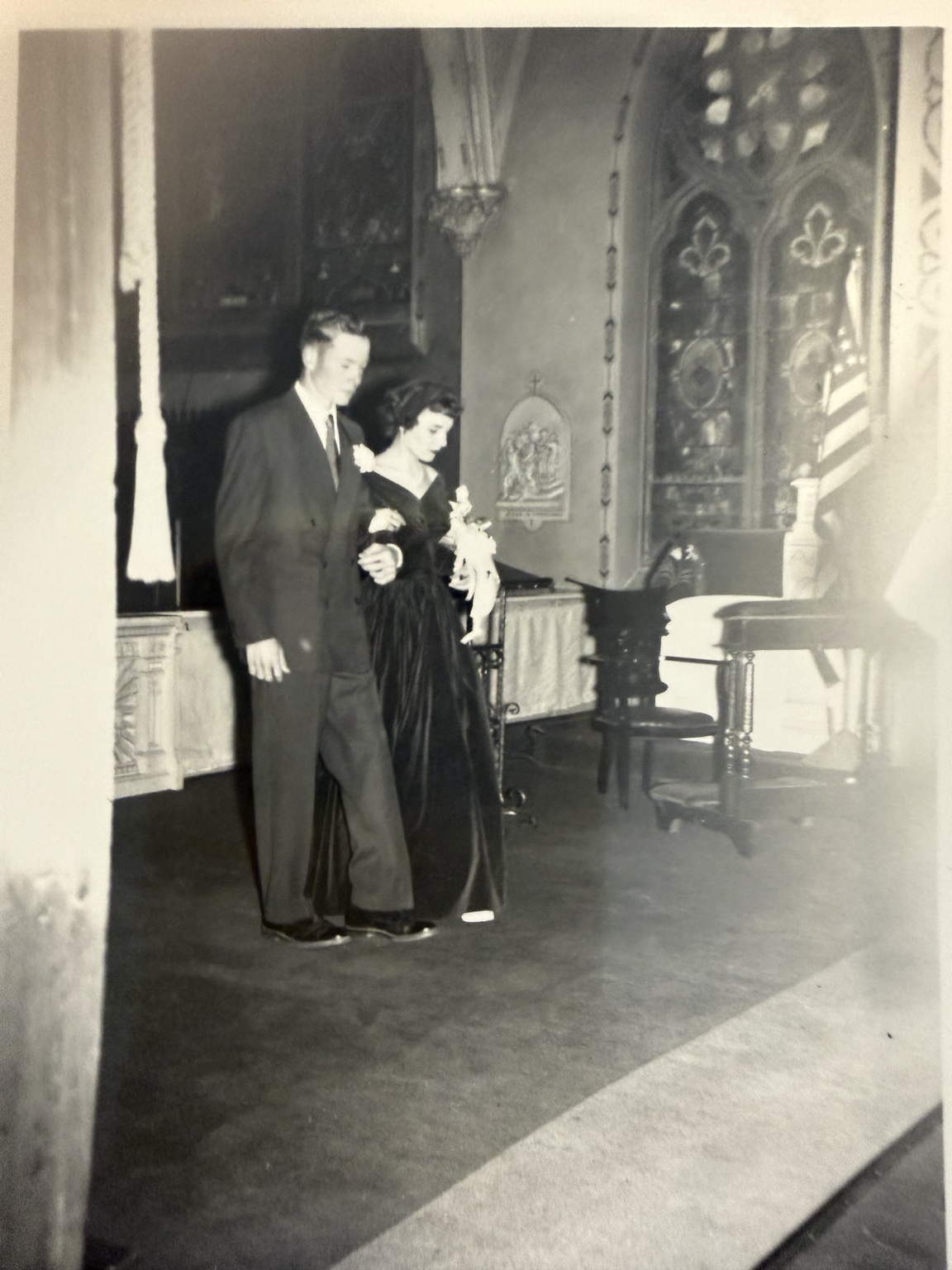 Two wedding-party members walking arm in arm in the church.